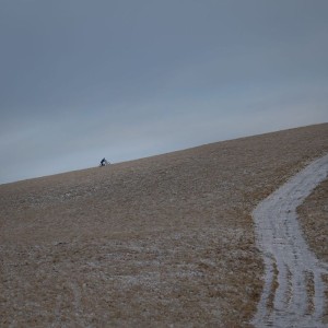 It'll be worth it when he comes down! A cyclist on the pushing up the Pentlands. February 2021